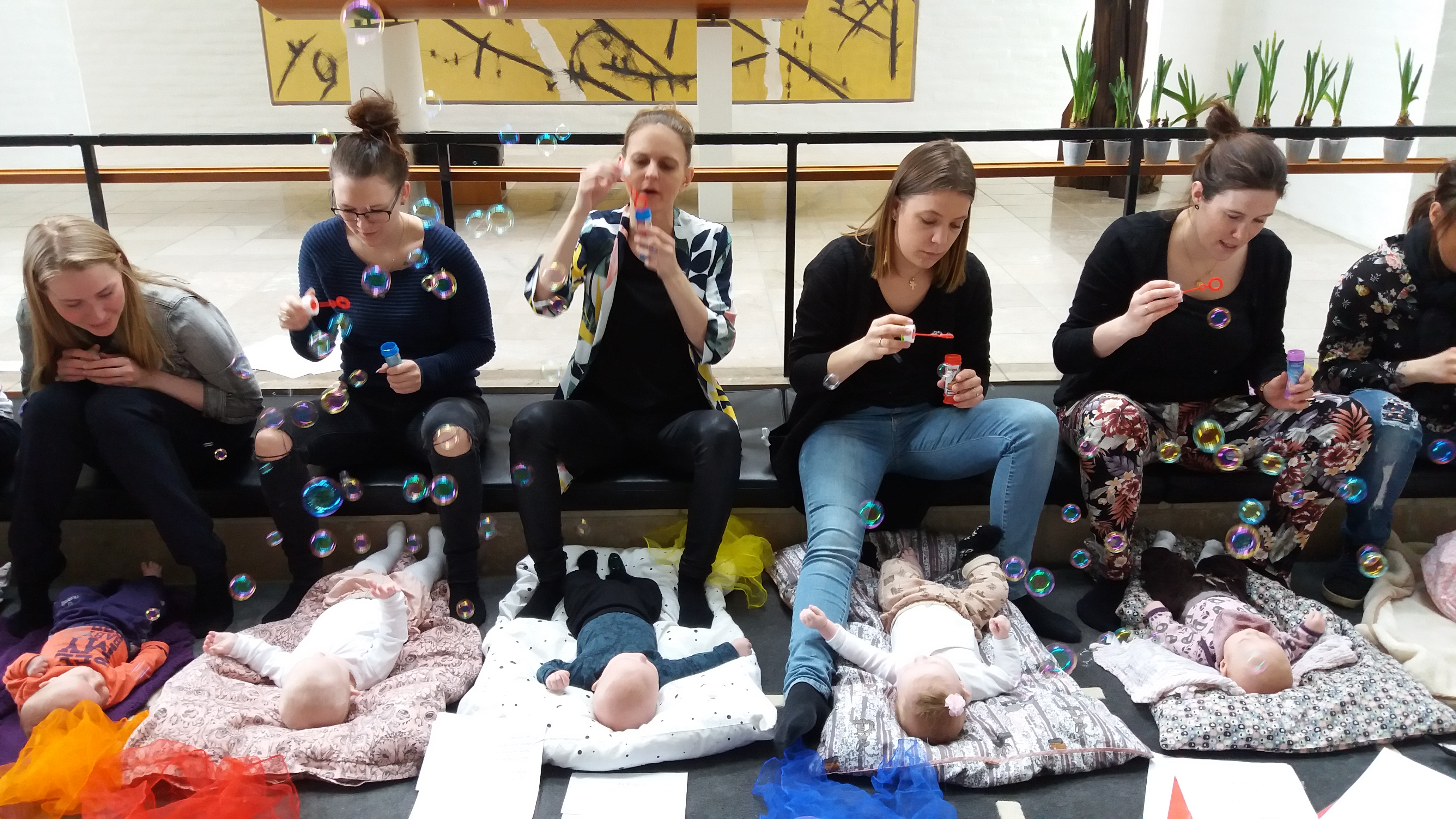 Mødre blæser sæbebobler på deres børn til babysalmesang